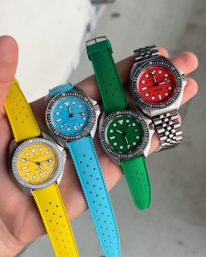Quatre montres de la collection JB200 Aquastrike de Jacques Bianchi, cadrans jaune, bleu, vert et rouge, tenues dans une main au Time Fest