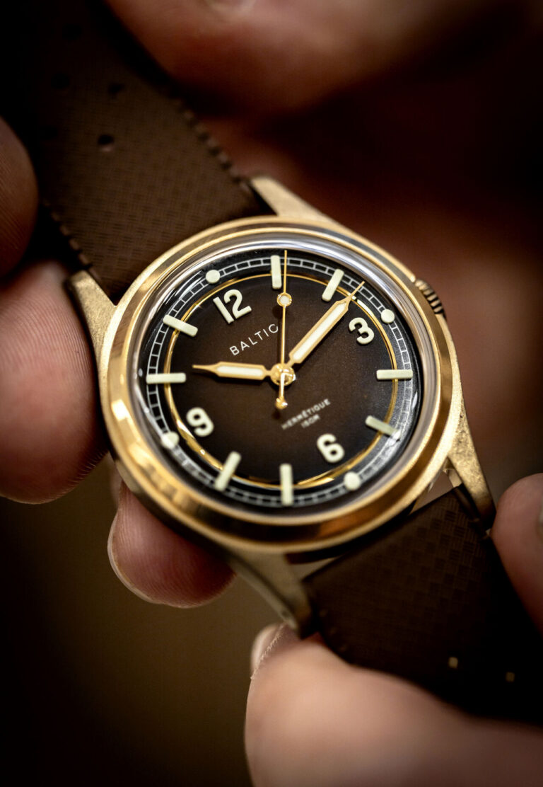 Soirée Baltic : les Heures du Monde Montre Baltic à cadran doré tenue en main, en gros plan