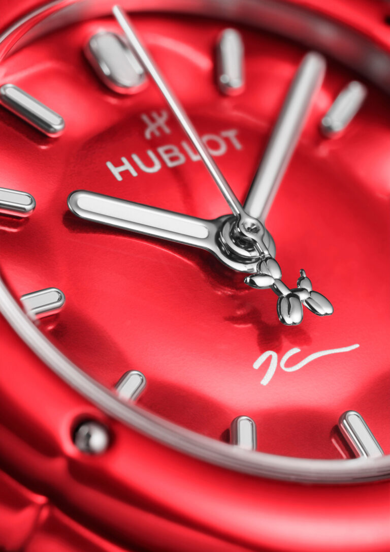 Détail du cadran rouge, index bombés en Super-LumiNova et signature de Jeff Koons à 6 heures